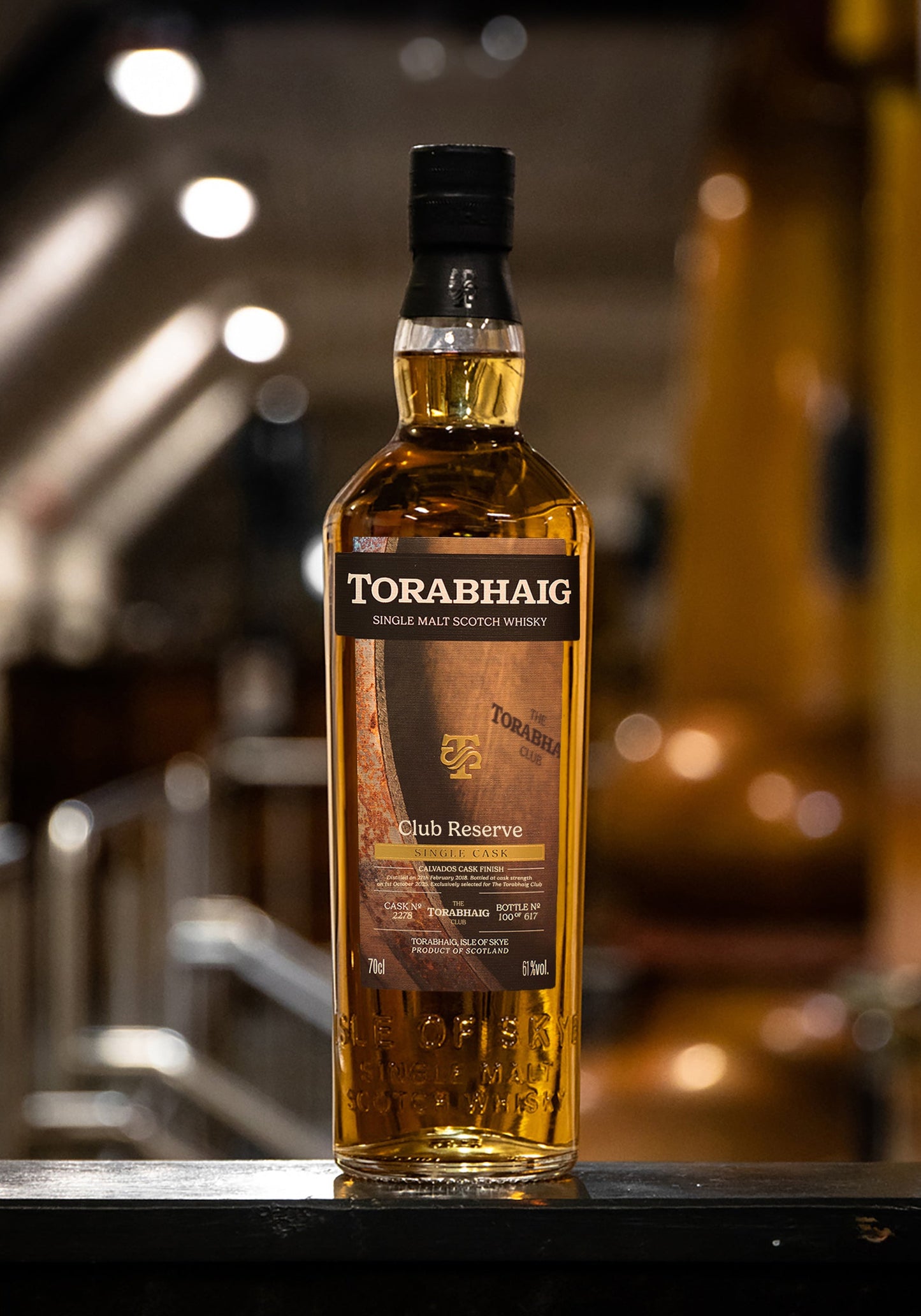 Torabhaig Club Reserve single malt whisky bottle on metal railing in distillery